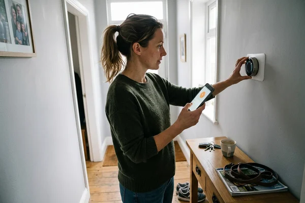 Homeowner adjusting a smart thermostat with the app open