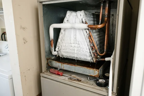 A frozen evaporator coil and frosted refrigerant line inside an air handler