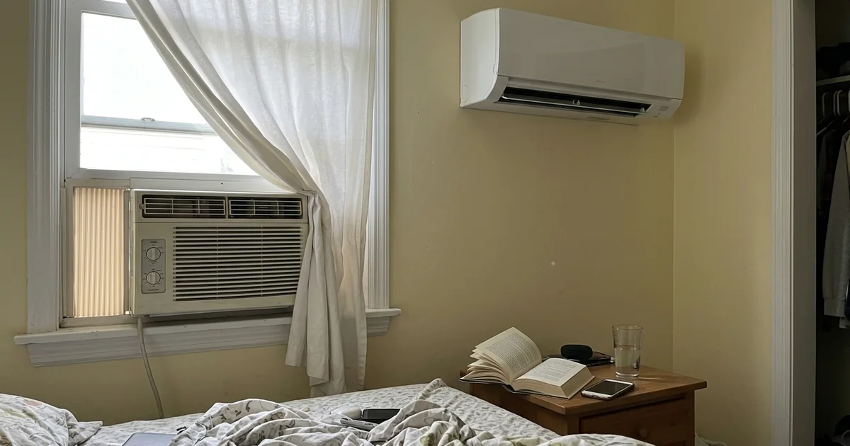 A window AC unit and a wall-mounted mini-split head in the same room